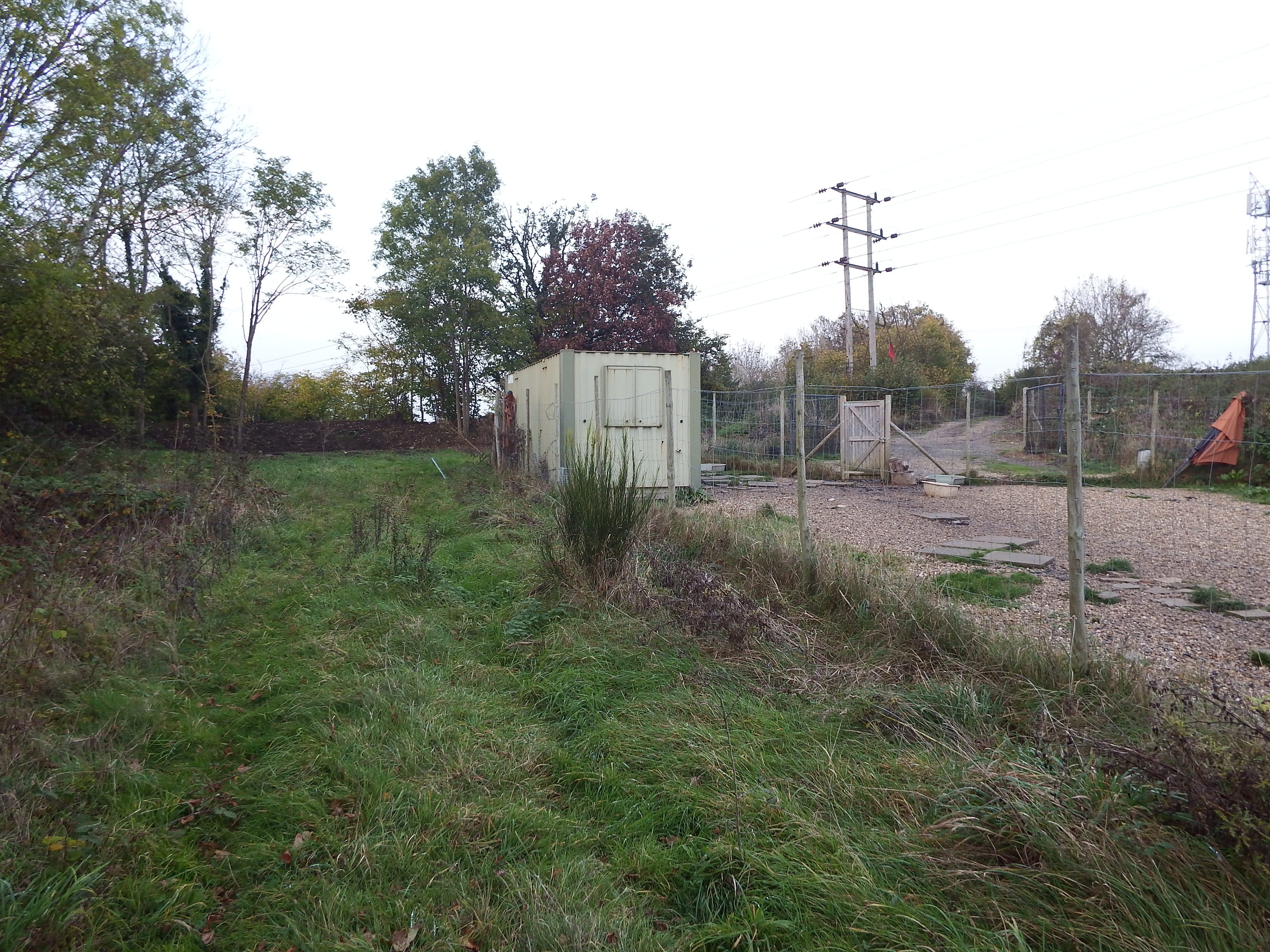 Looking north. The site is behind container with bund beyond. Access track is to right of Electricity poles.